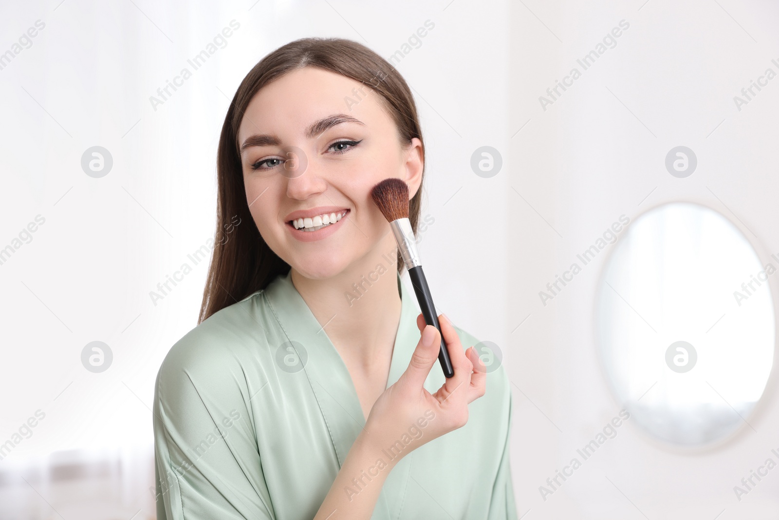 Photo of Beautiful young woman applying makeup with brush at home. Space for text