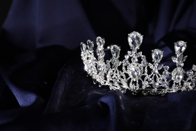 Beautiful silver tiara with diamonds on dark blue cloth. Space for text