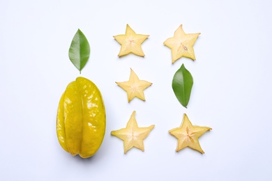 Photo of Delicious carambola fruits and leaves on white background, flat lay