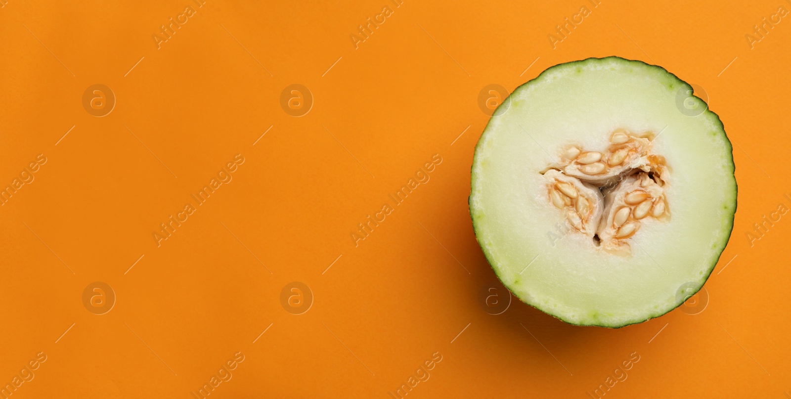 Photo of Half of ripe tasty melon on orange background, top view. Space for text