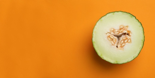 Half of ripe tasty melon on orange background, top view. Space for text