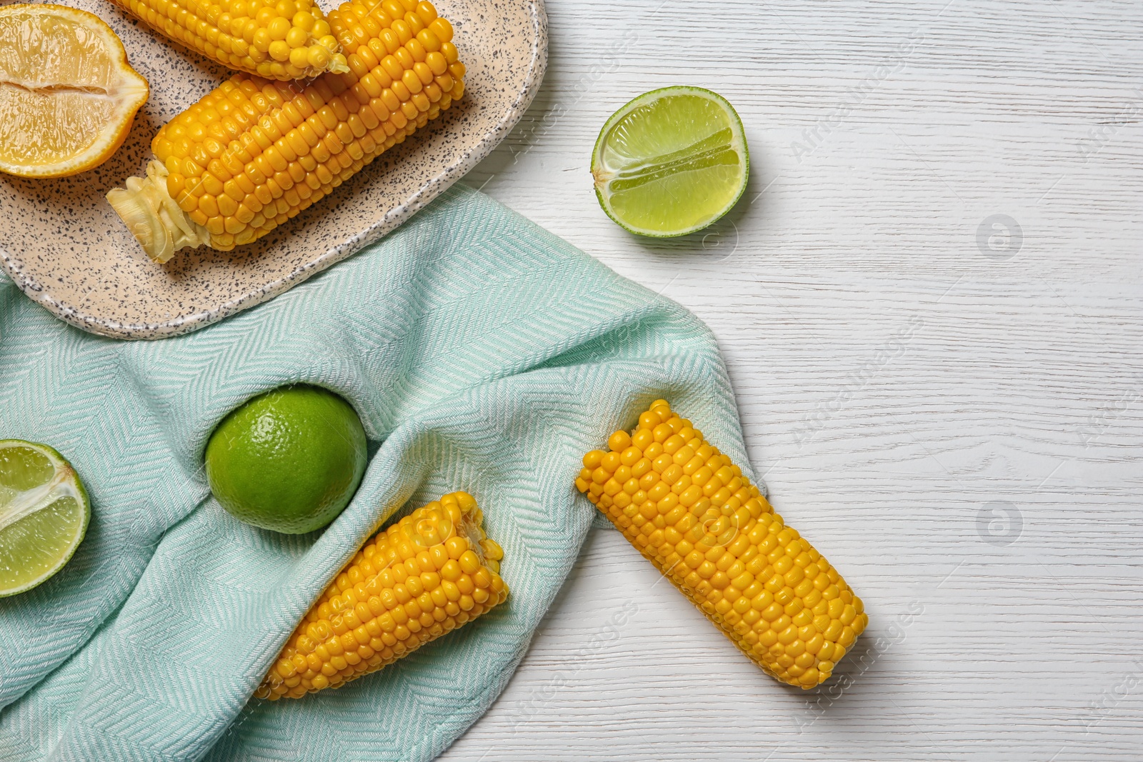 Photo of Flat lay composition with corn cobs and citrus fruits on white wooden background. Space for text