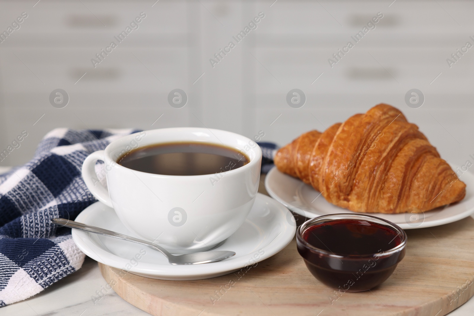 Photo of Breakfast time. Fresh croissant, coffee and jam on white table, closeup