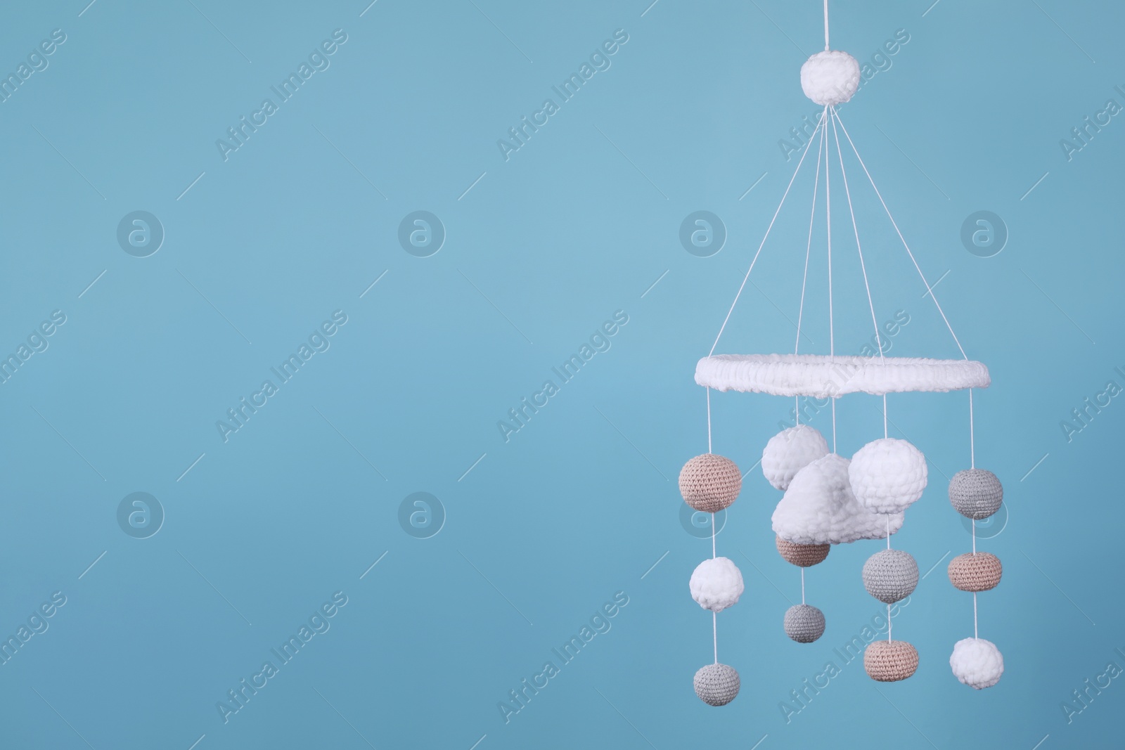 Photo of Cute baby crib mobile on light blue background, space for text