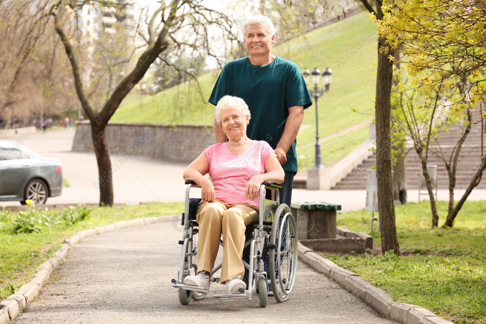 Photo of Senior woman in wheelchair and mature man on sunny day outdoors