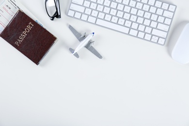 Flat lay composition with airplane model and computer keyboard on light background. Travel agency concept