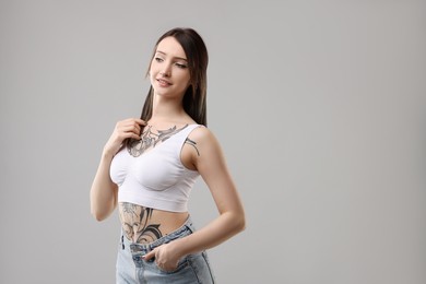 Portrait of beautiful tattooed woman on grey background