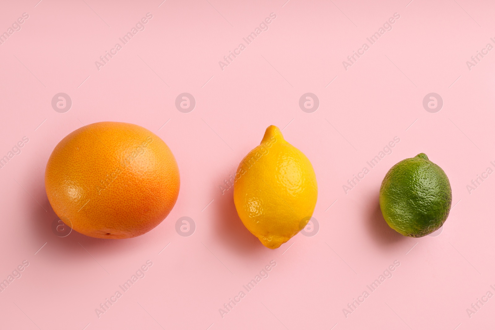 Photo of Grapefruit, lemon and lime on pink background, flat lay