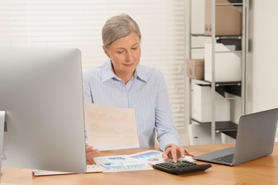 Photo of Senior accountant working at wooden desk in office