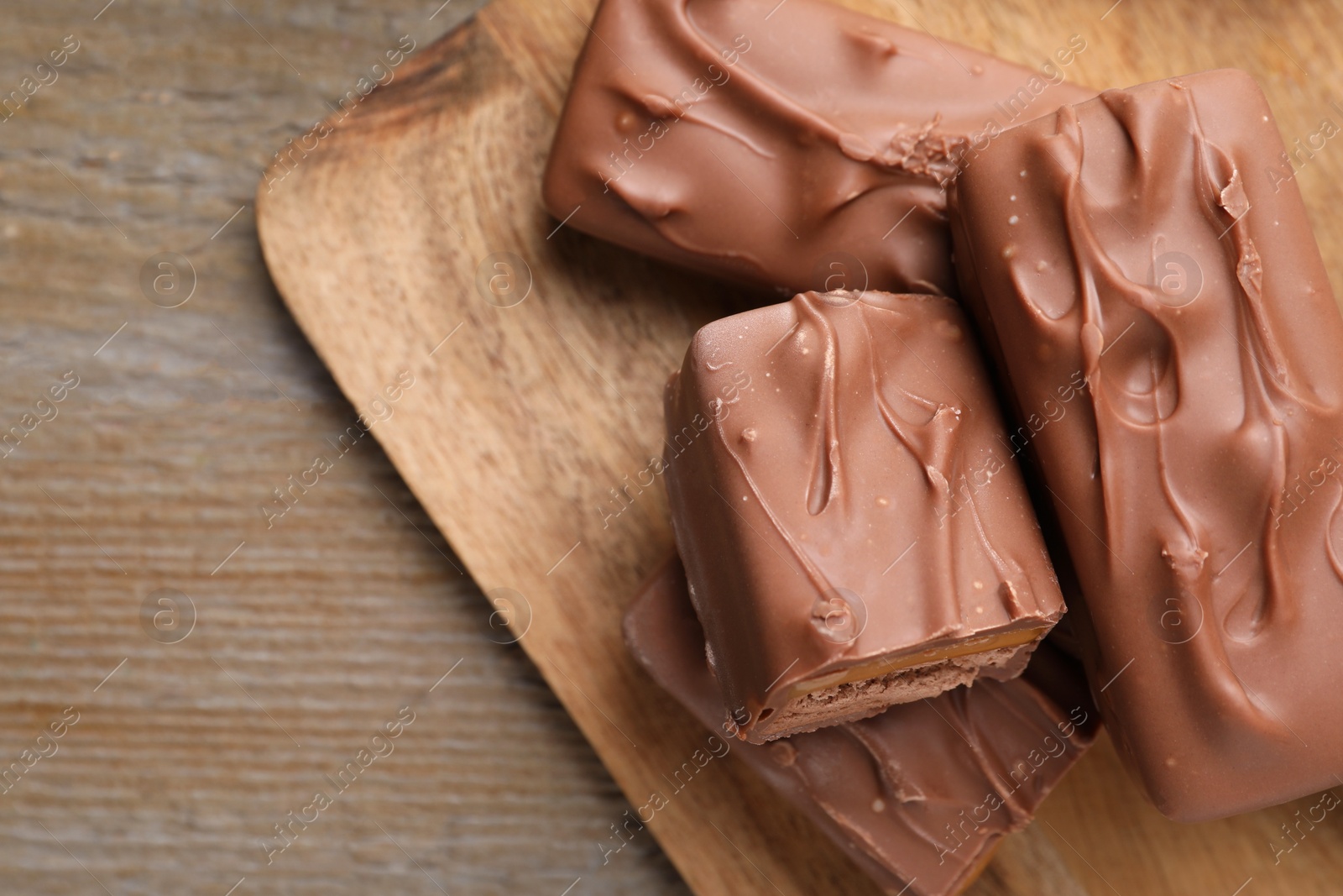 Photo of Tasty chocolate bars with nougat on wooden table, top view. Space for text