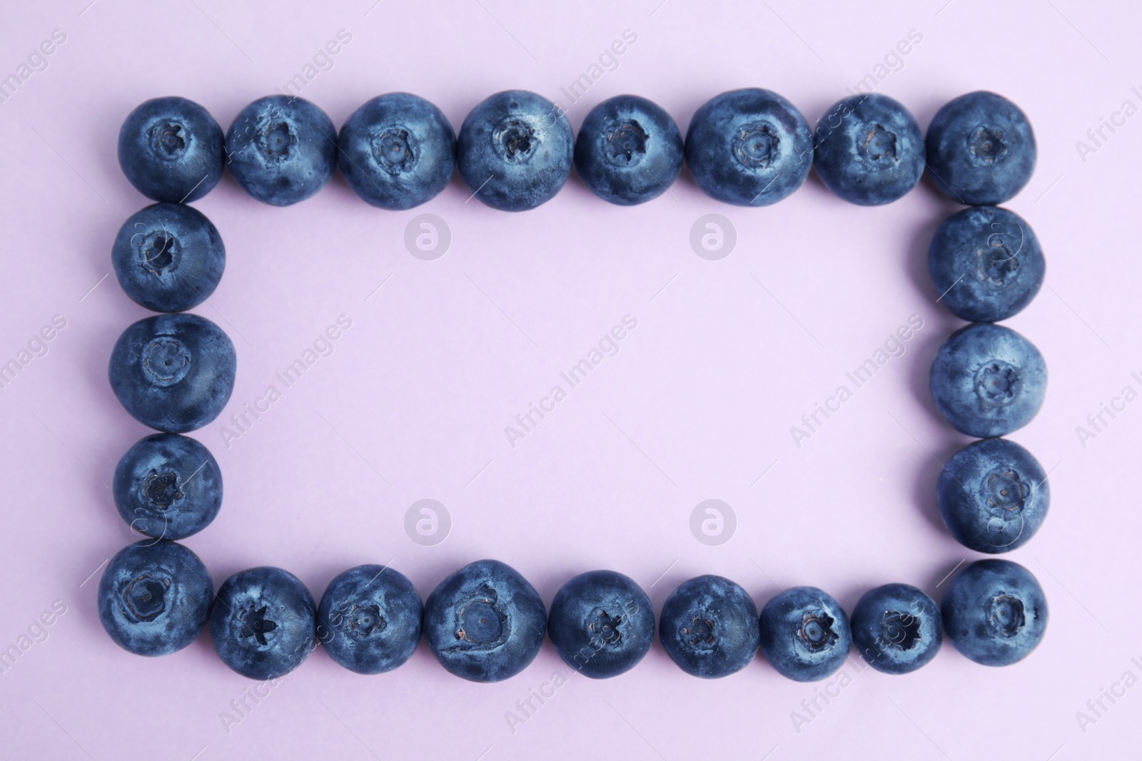 Photo of Frame of fresh ripe blueberries on lilac background, flat lay. Space for text