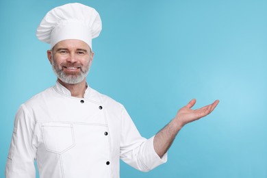Happy chef in uniform posing on light blue background
