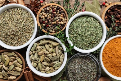 Flat lay composition with different natural spices and herbs on wooden table