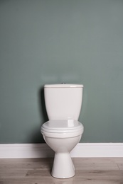 Photo of New ceramic toilet bowl near grey wall