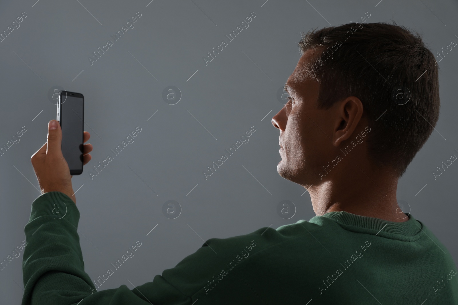 Photo of Man unlocking smartphone with facial scanner on grey background. Biometric verification