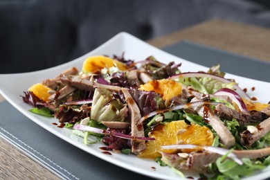 Delicious salad with beef tongue, orange and onion on wooden table, closeup