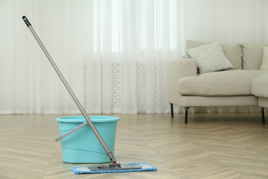 Bucket and mop on floor at home, space for text. Cleaning equipment