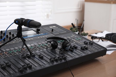 Photo of Professional audio equipment on wooden table in modern radio studio