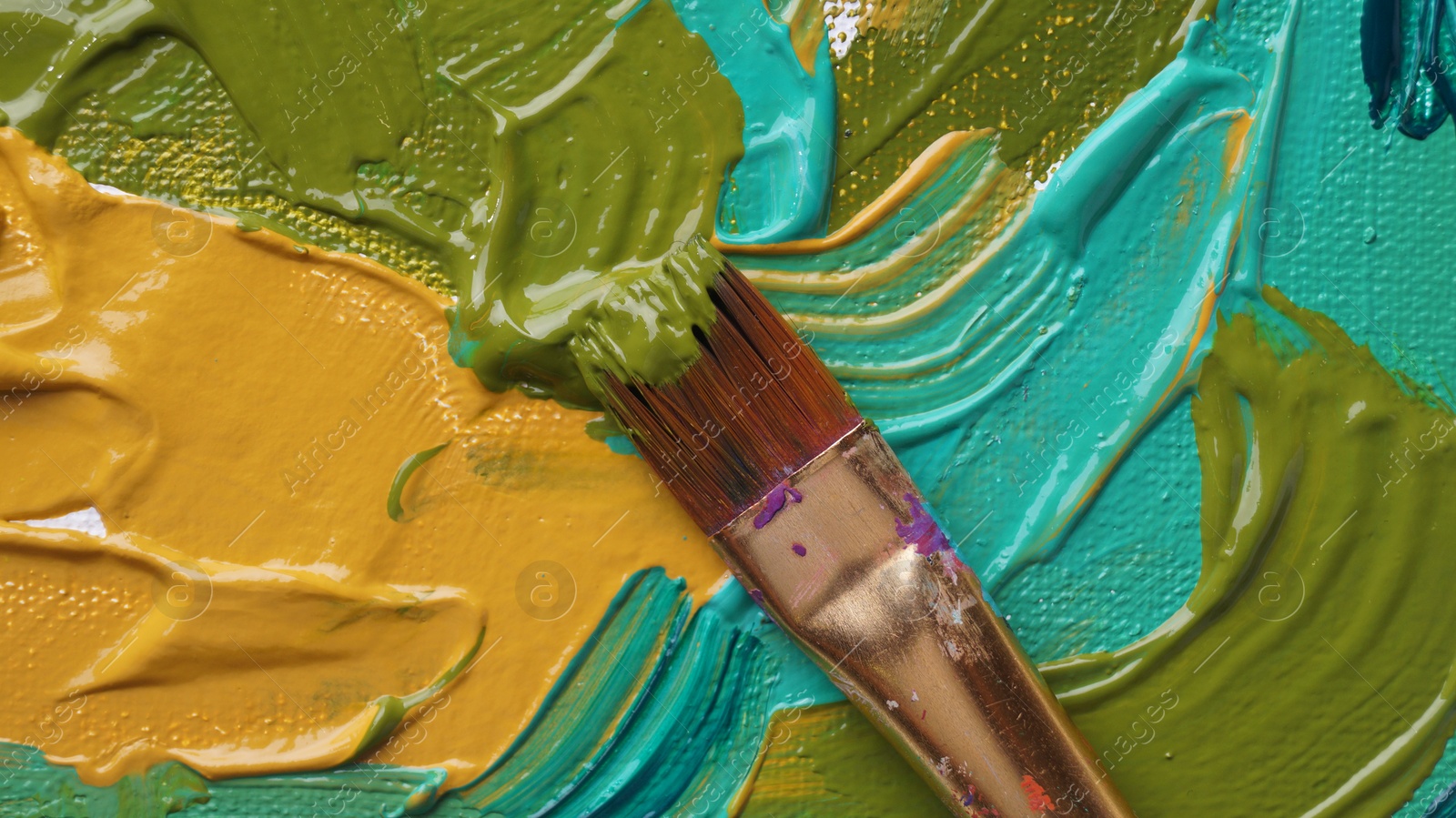 Photo of Brush on artist's palette with mixed paints, top view