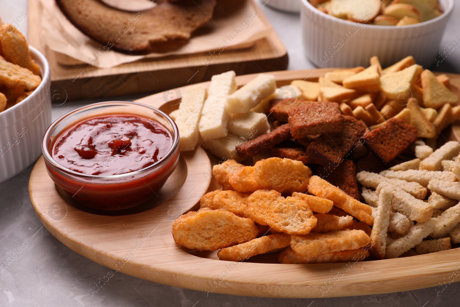 Photo of Different crispy rusks with dip sauce on light table, closeup
