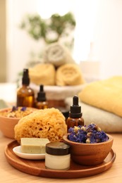 Photo of Dry flowers, loofah, soap bar, bottle of essential oil and jar with cream on wooden table indoors. Spa time