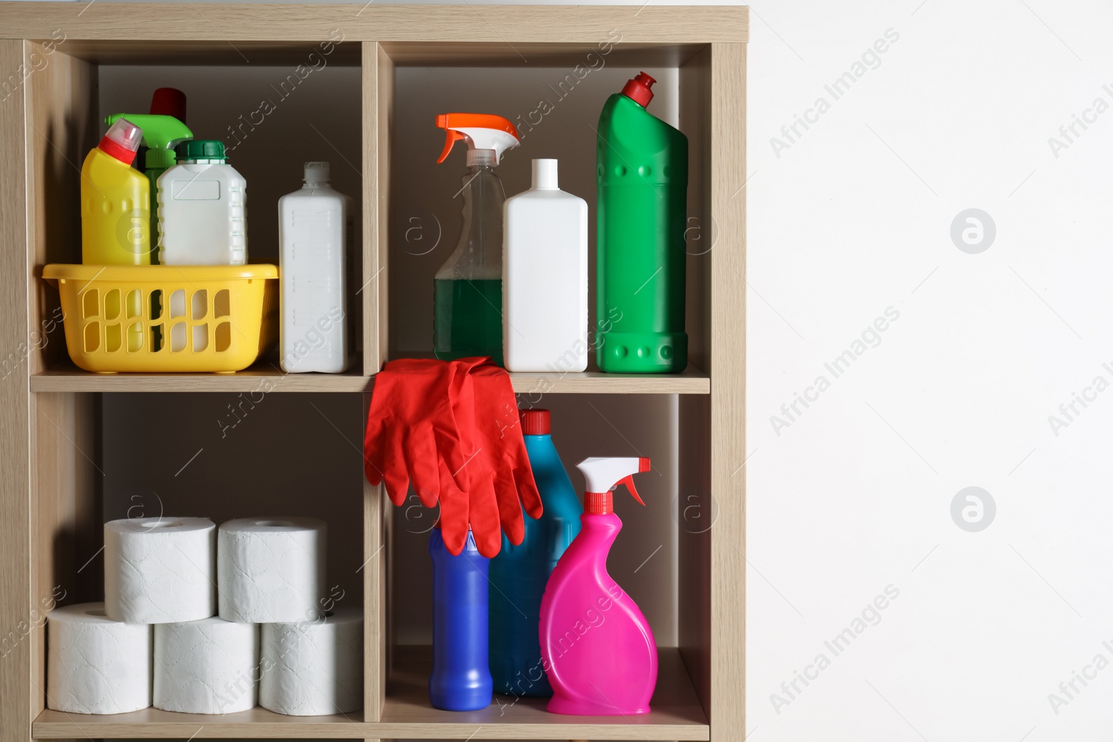 Photo of Shelving unit with detergents and toilet paper on white background, space for text