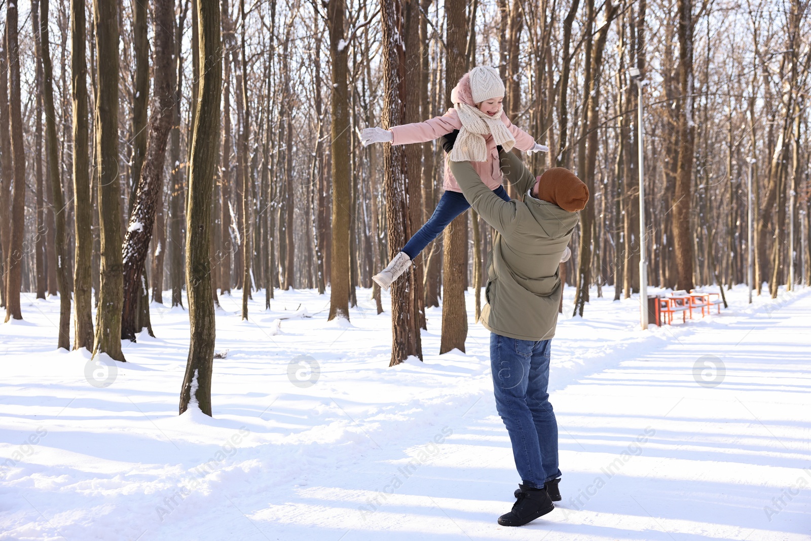 Photo of Family time. Father playing with his daughter in snowy forest. Space for text