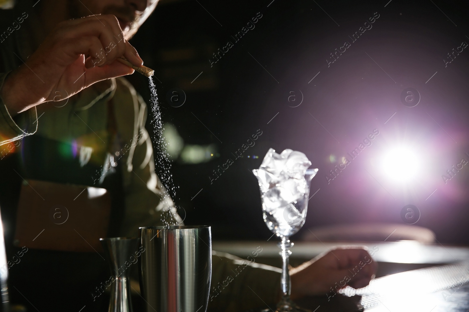 Photo of Barman pouring sugar into shaker at counter, closeup with space for text. Making martini cocktail