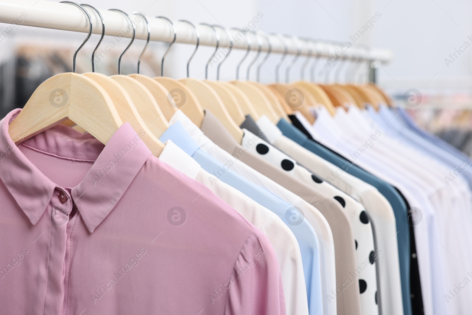 Photo of Dry-cleaning service. Many different clothes hanging on rack indoors, closeup