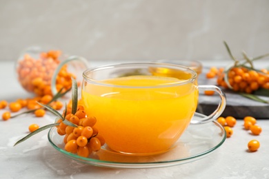 Delicious sea buckthorn tea and fresh berries on light grey table