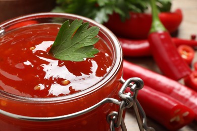 Photo of Spicy chili sauce with parsley in glass jar, closeup