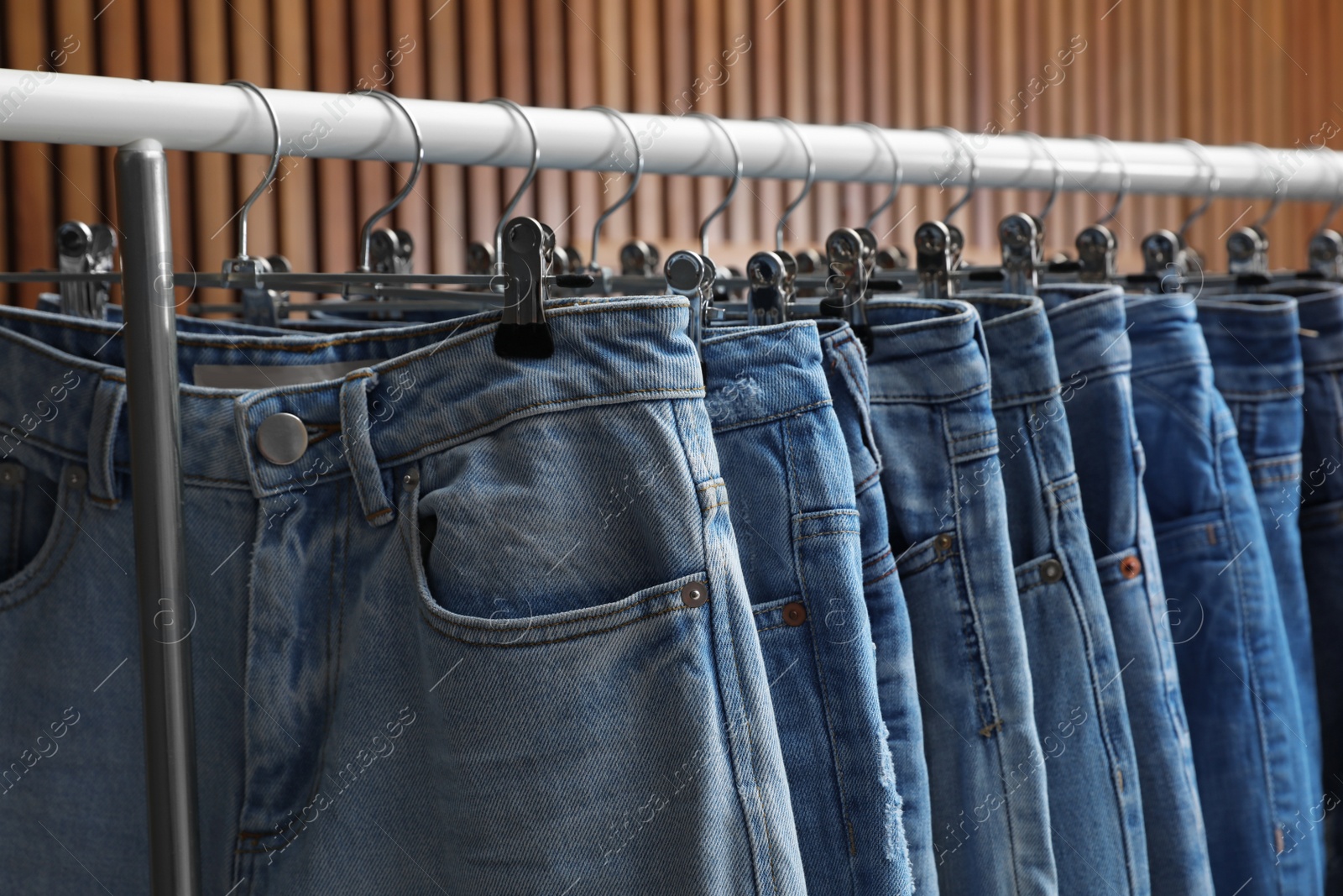 Photo of Rack with different jeans on wooden background, closeup