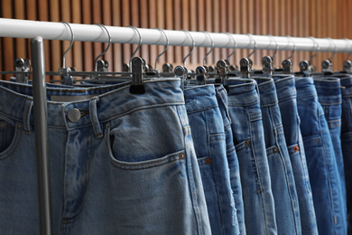 Photo of Rack with different jeans on wooden background, closeup