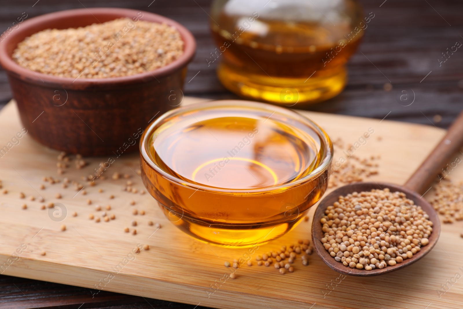 Bowl of natural oil and mustard seeds on wooden table, closeup Photo of Bowl of natural oil and mustard seeds on wooden table, closeup