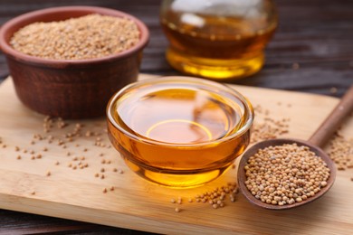 Photo of Bowl of natural oil and mustard seeds on wooden table, closeup