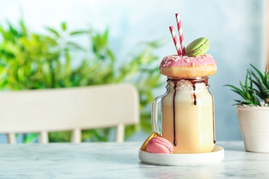 Mason jar with delicious milk shake on table against blurred background. Space for text