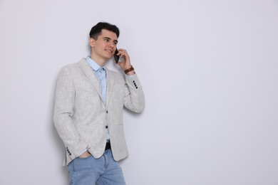 Photo of Handsome young man talking on phone against white background, space for text