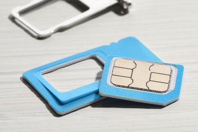 Photo of Multi SIM card on white wooden background, closeup