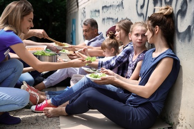 Photo of Poor people receiving food from volunteers outdoors
