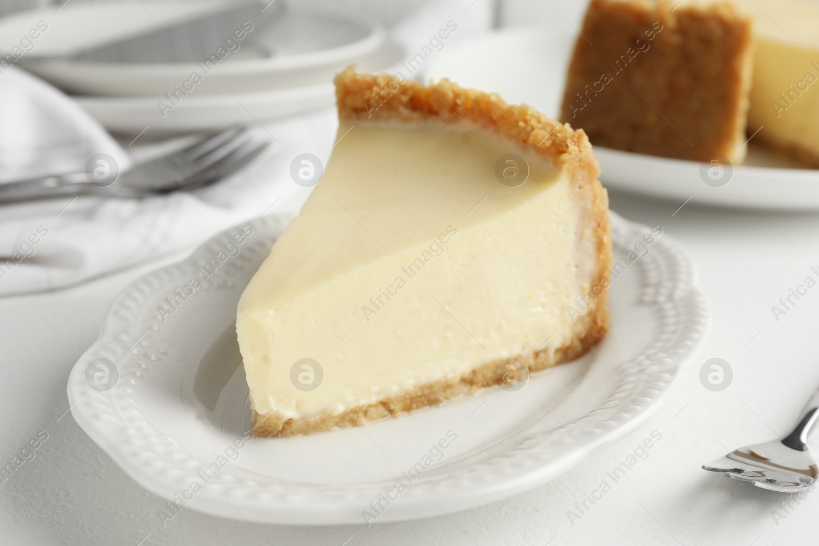 Photo of Piece of tasty vegan tofu cheesecake and fork on white table, closeup