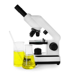 Photo of Laboratory glassware with yellow liquid and microscope isolated on white