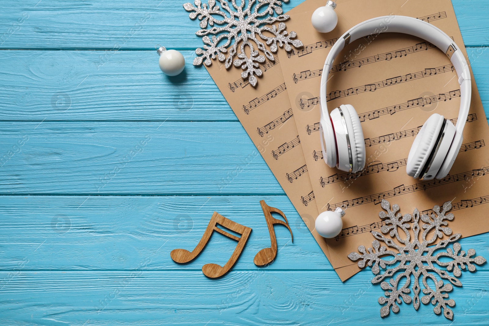Photo of Flat lay composition with Christmas decorations, headphones and music sheets on blue wooden table, space for text