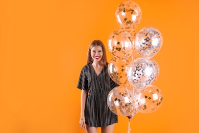 Photo of Young woman with air balloons on color background