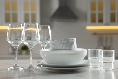 Photo of Different clean dishware and glasses on white marble table in kitchen