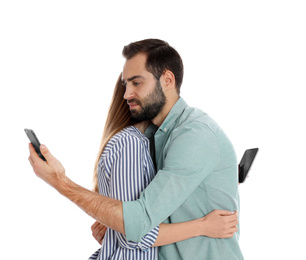 Photo of Couple addicted to smartphones hugging on white background. Relationship problems