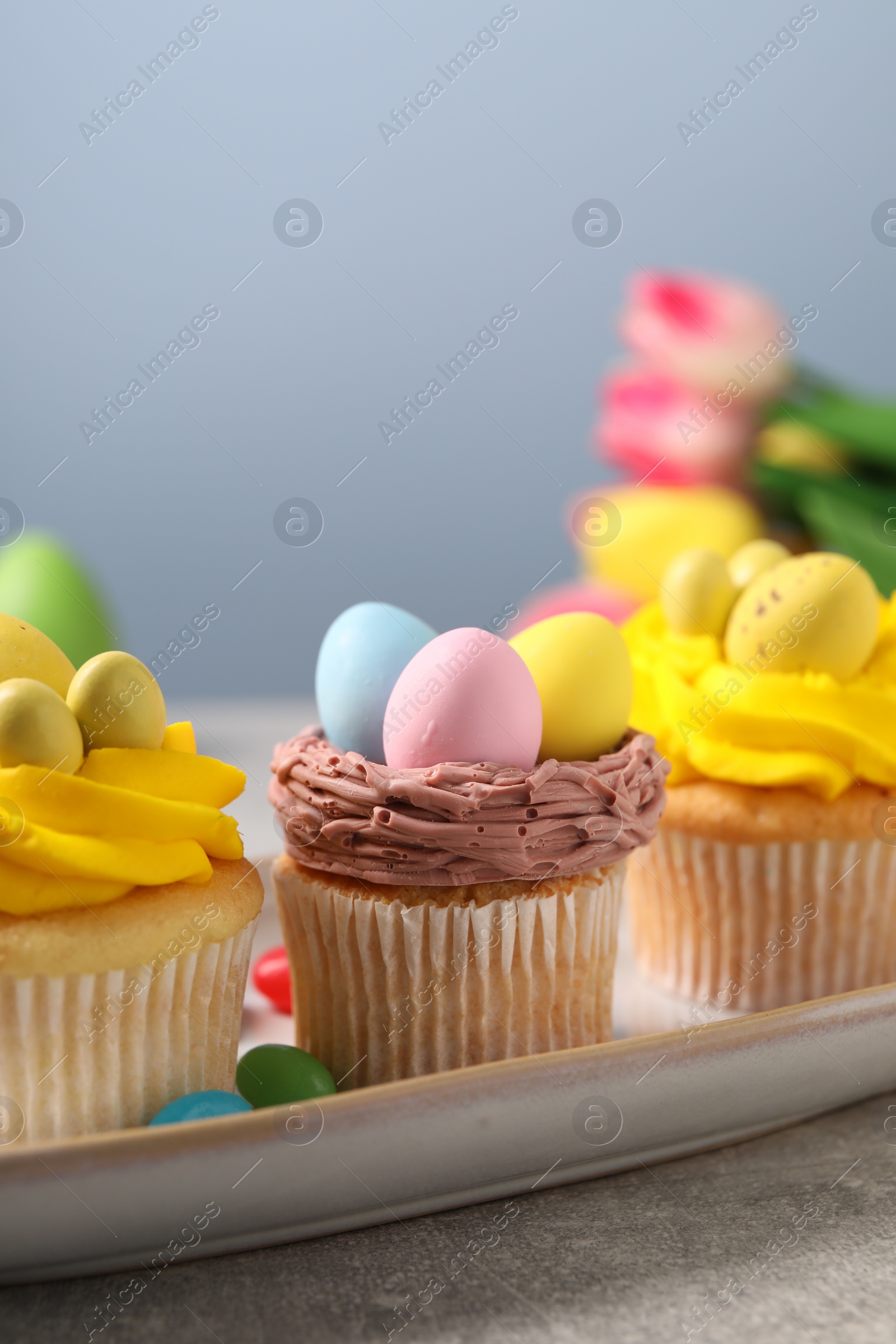 Photo of Tasty decorated Easter cupcakes on grey table, closeup