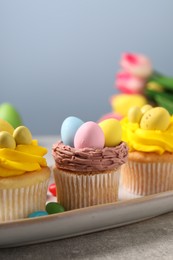 Photo of Tasty decorated Easter cupcakes on grey table, closeup