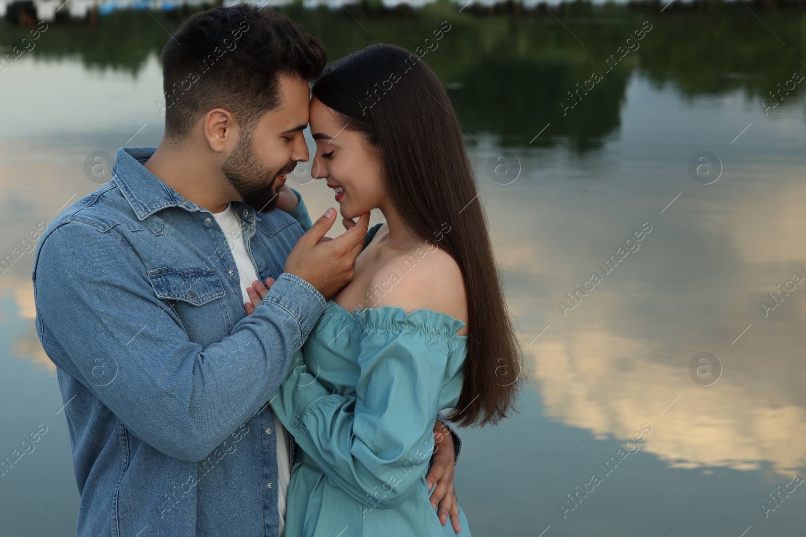 Photo of Romantic date. Beautiful couple spending time together near lake, space for text