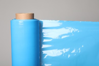 Photo of Roll of turquoise stretch wrap on grey background, closeup
