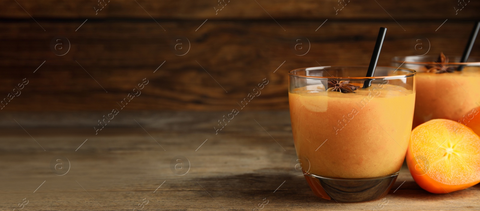 Image of Tasty persimmon smoothie with anise and straw on wooden table, space for text. Banner design